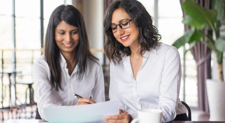 two-smiling-female-coworkers-planning-cafe_1262-12593