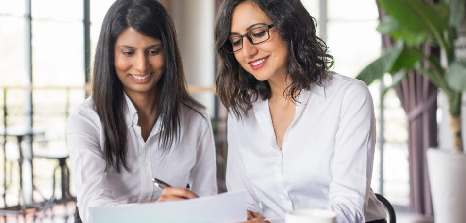 two-smiling-female-coworkers-planning-cafe_1262-12593